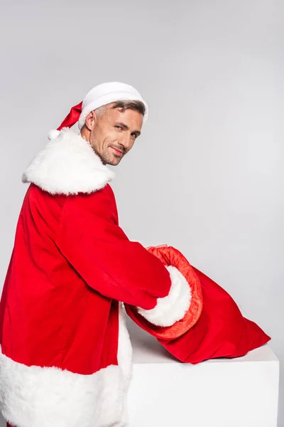 Stilig Man Santa Dräkt Holding Röd Väska Och Ler Mot — Stockfoto