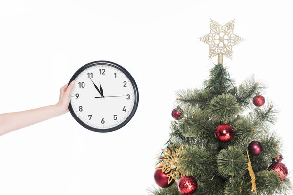 cropped shot of woman holding clock near christmas tree isolated on white