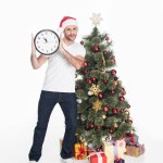 Homme en santa claus chapeau avec horloge debout près de l'arbre de Noël isolé sur blanc