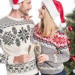 Ungt par i kärlek klirrande glas champagne nära julgran isolerad på vit