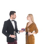 Homem elegante que apresenta o presente à amiga sorridente com copo de champanhe isolado no branco