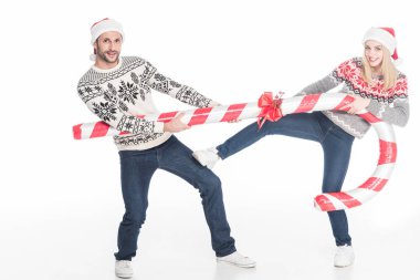 Noel Baba şapkaları ve üzerinde beyaz izole oyuncak şeker üzerine çekerek kazak genç çift