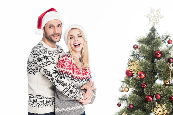 Young Couple Santa Claus Hats Hugging Christmas Tree Isolated White — Free Stock Photo