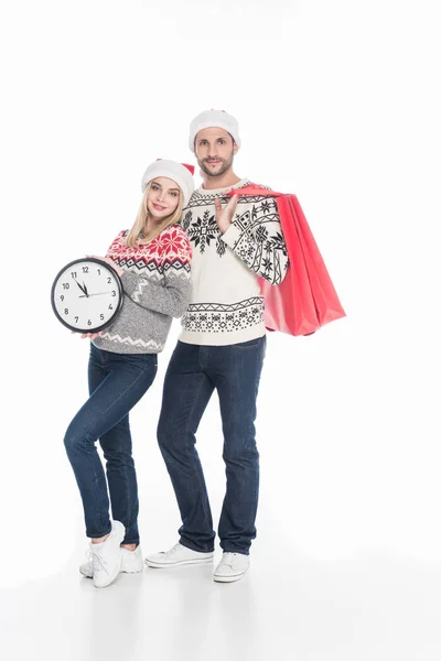 Pareja Joven Suéteres Sombreros Santa Claus Con Bolsas Compras Reloj — Foto de stock gratis