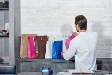 arkadan görünüşü ile kağıt torbalar dükkanda çalışan genç adam 