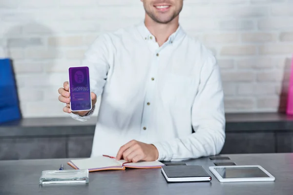 Bijgesneden Schot Van Glimlachen Jonge Verkoper Smartphone Met Winkelen Toepassing — Gratis stockfoto