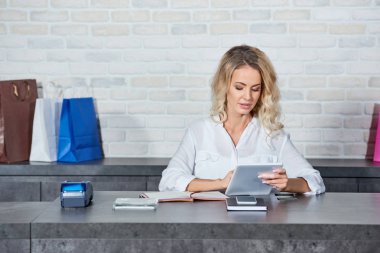 Genç kadın satıcı dükkanda çalışırken dijital tablet kullanma