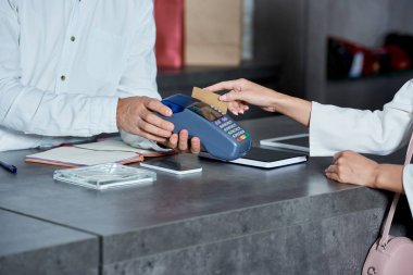 ödeme terminal holding işçi ve kadın dükkanda kredi kartıyla ödeme kırpılmış