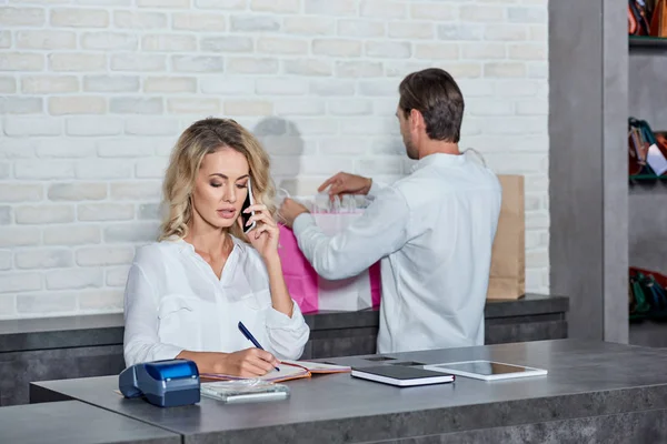 Junge Frau Macht Sich Notizen Und Spricht Mit Smartphone Während — Stockfoto