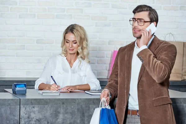 Smiling Man Holding Shopping Bags Talking Smartphone While Female Seller — Stock Photo, Image