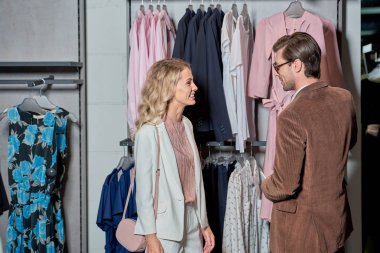 smiling young couple choosing fashionable clothes in shop clipart