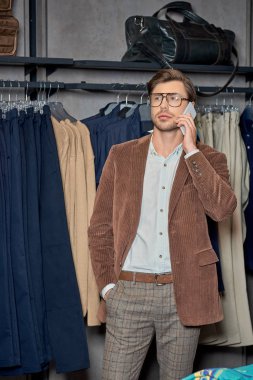 handsome man talking by smartphone while shopping in boutique     clipart
