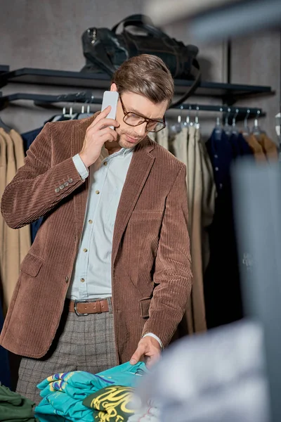Homem Bonito Falando Por Smartphone Olhando Para Roupas Elegantes Loja — Fotografia de Stock Grátis