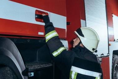 kadın itfaiyeci itfaiye kamyon kapı kolundan tutarak yan görünüm