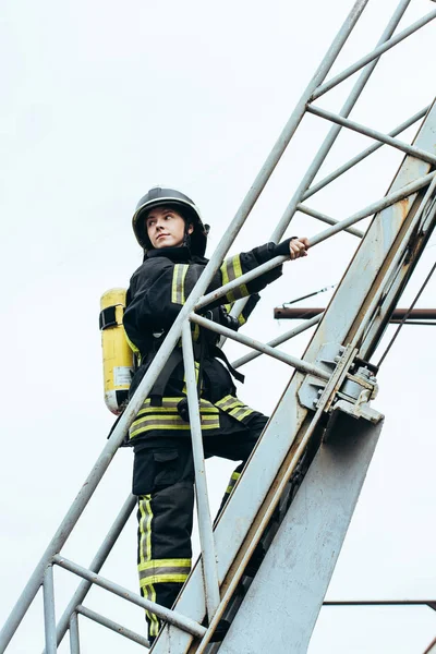 Пожарная Женщина Защитной Форме Шлеме Огнетушителем Спине Стоит Лестнице Голубым — Бесплатное стоковое фото
