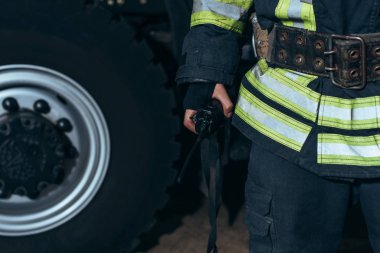 partial view of firefighter with portable radio set at fire station clipart