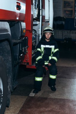 Taşınabilir radyo ile koruyucu üniformalı kadın itfaiyeci itfaiye kamyonette oturan ayarla