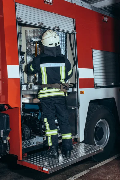 Achteraanzicht Van Brandweerman Brandvrije Uniform Helm Staande Buurt Van Vrachtwagen — Gratis stockfoto