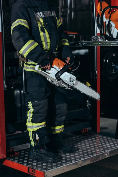 Częściowy Widok Strażaka Mundurze Ochronne Gospodarstwa Elektryczne Zobaczył Ręce Straży — Darmowe zdjęcie stockowe