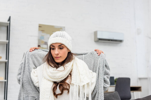 freezed young woman putting on warm clothes at home