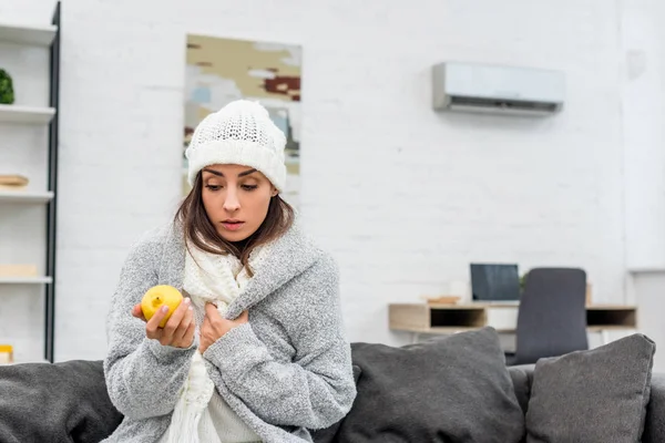 生病的年轻妇女在温暖的衣服在家里拿着柠檬 — 图库照片