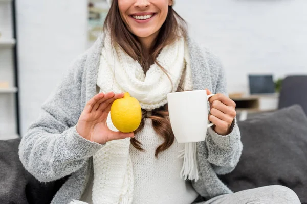 家でレモンを抱えて暖かい服で笑顔の若い女性のショットをトリミング — ストック写真