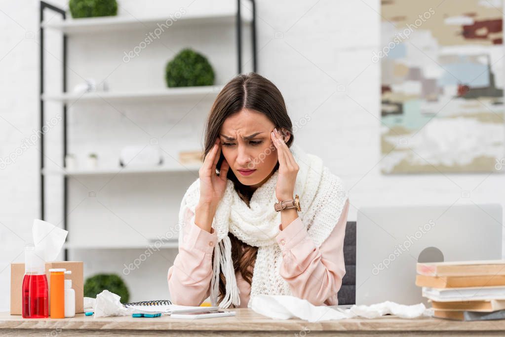 sick young businesswoman suffering from headache at workplace