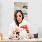 Sick young businesswoman pouring cough syrup at workplace