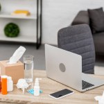 Close-up shot of messy office workplace with laptop and various medicines