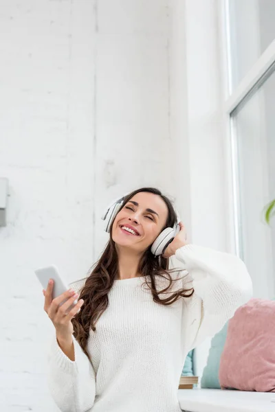 Mujer Joven Sonriente Escuchando Música Con Smartphone Auriculares Inalámbricos Casa — Foto de Stock