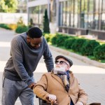 Senior disabled man in wheelchair and african american man talking on street