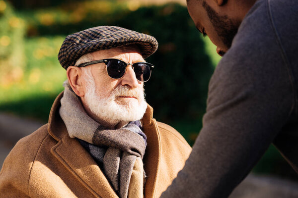 close-up shot of senior man looking at african american man on street