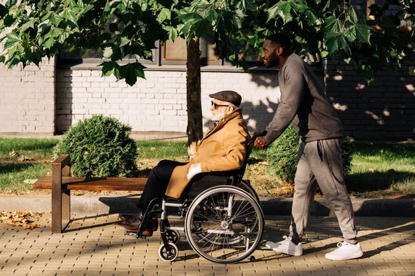 Vista Lateral Del Anciano Discapacitado Silla Ruedas Enfermera Cabalgando Calle — Foto de Stock