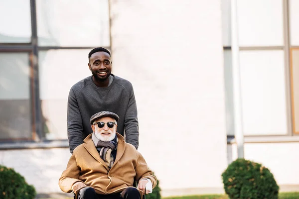 Χαμογελαστά Ανώτερος Απενεργοποιημένη Άνδρα Αναπηρικό Καροτσάκι Και Αφρικανική Αμερικανική Άνθρωπος — Δωρεάν Φωτογραφία