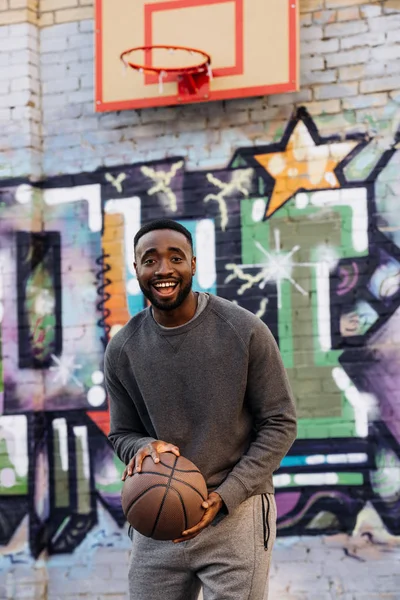 Hombre Afroamericano Feliz Con Pelota Baloncesto Mirando Cámara Calle Delante — Foto de Stock