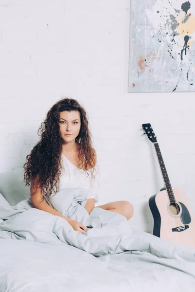 Schöne Junge Frau Sitzt Bett Neben Akustikgitarre Hause — kostenloses Stockfoto