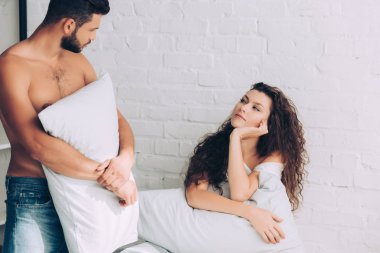 yakışıklı kaslı adam yastık tutarak ve kız evde yatak odasında konuştuğu kot pantolon