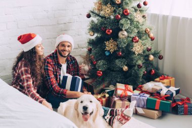 Noel Baba şapkaları ve Noel ağacı evde yakınındaki altın geri almak genç çiftin yüksek açılı görünüş