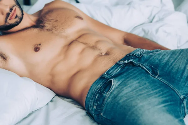 自宅の寝室で敷設筋肉胴で上半身裸の男の画像をトリミング — ストック写真