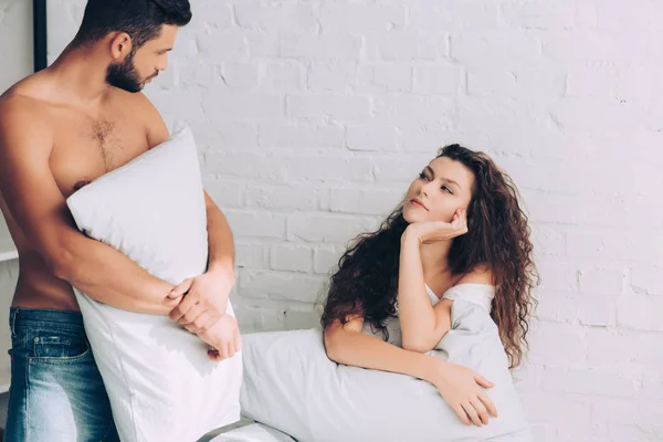 Guapo Musculoso Hombre Jeans Sosteniendo Almohada Hablando Con Novia Dormitorio — Foto de Stock