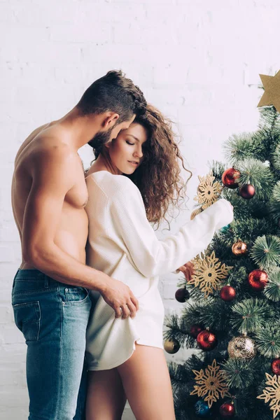 Shirtless Muscular Man Embracing Attractive Girlfriend Christmas Tree Home — Stock Photo, Image