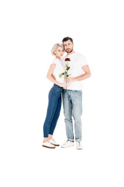 Çekici genç yetişkin çift kameraya bakarken çiçek sarılmakla beyaz izole 