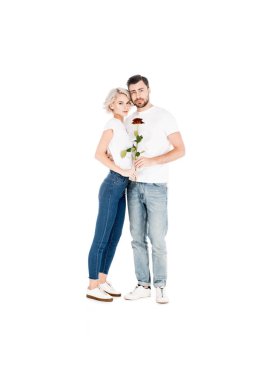 Attractive young adult couple with flower hugging while looking at camera isolated on white  clipart
