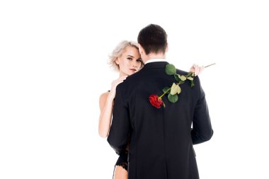 Back view of man in black costume hugging fantastic blonde woman with flower isolated on white clipart