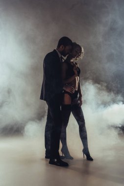 Arka plan gri şefkatle kucaklayan genç yetişkin çekici çift duman