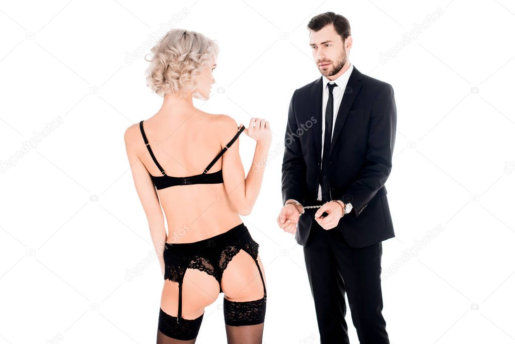 Couple of young adults looking at each other while man is in handcuffs and woman in lingerie isolated on white