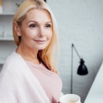 Attrayant mature blonde femme tenant tasse de café blanc
