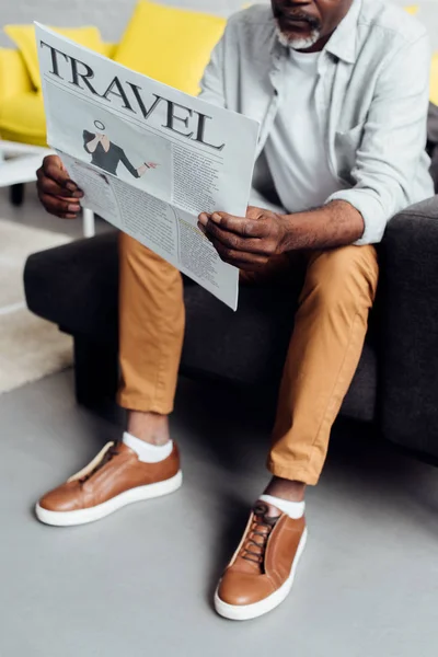 African American Man Sitting Sofa Reading Travel Newspaper — Free Stock Photo