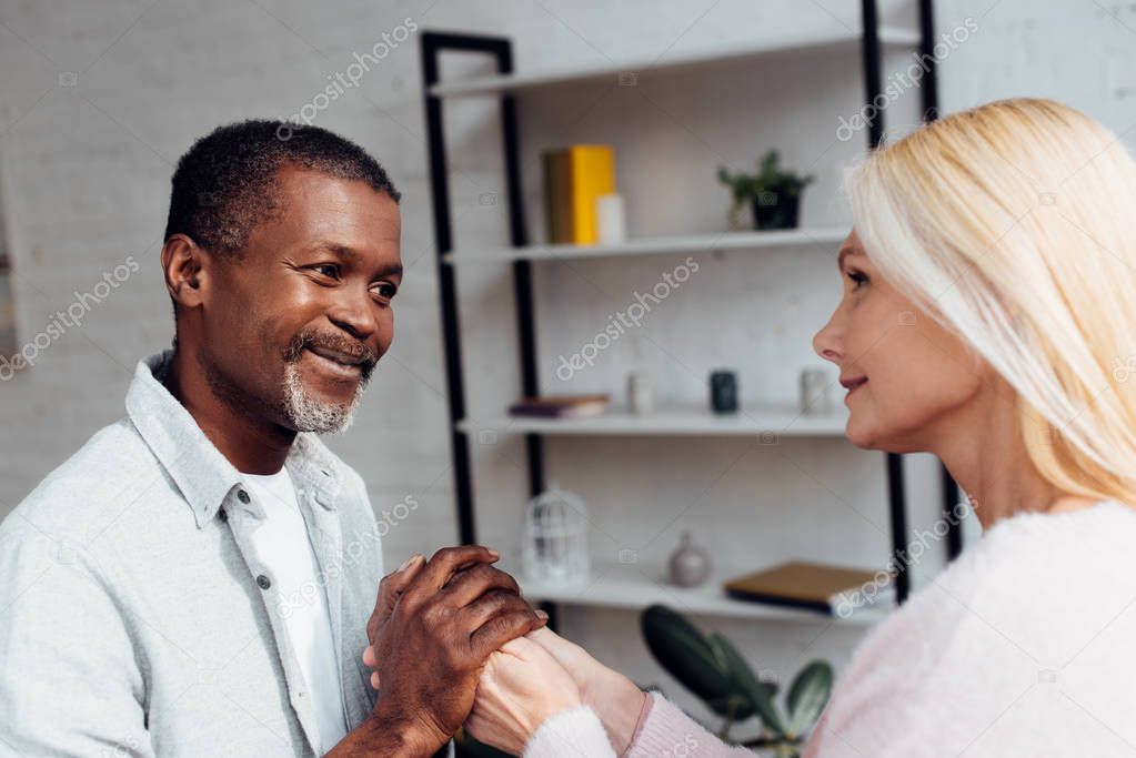 mature woman and african american man holding hands together 