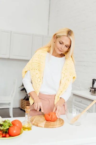 有吸引力的金发碧眼的女人切番茄在切菜板上 — 图库照片